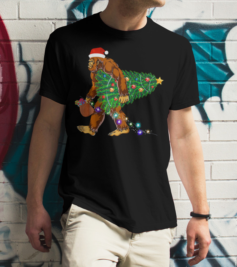 Santa Hat Bigfoot Holding Christmas Tree With Lights And Gifts T-Shirt